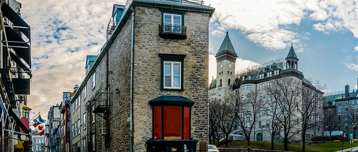The streets of old Quebec City with thin intertwining stone town housing and a clock tower building.