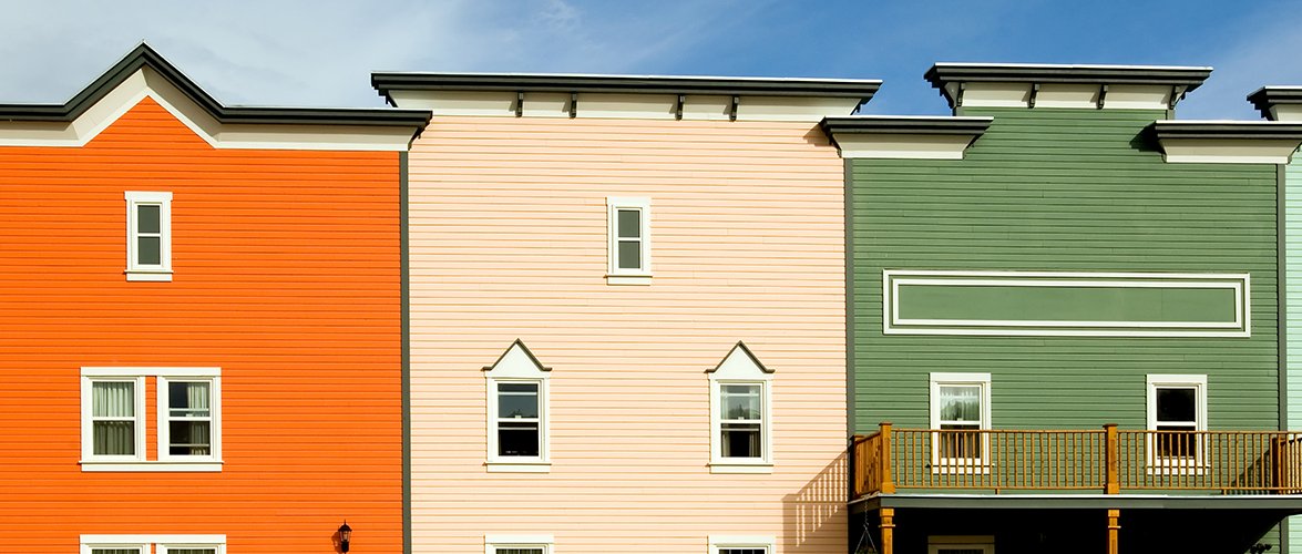 Large colourful town homes painted bright orange, light salmon and olive green.