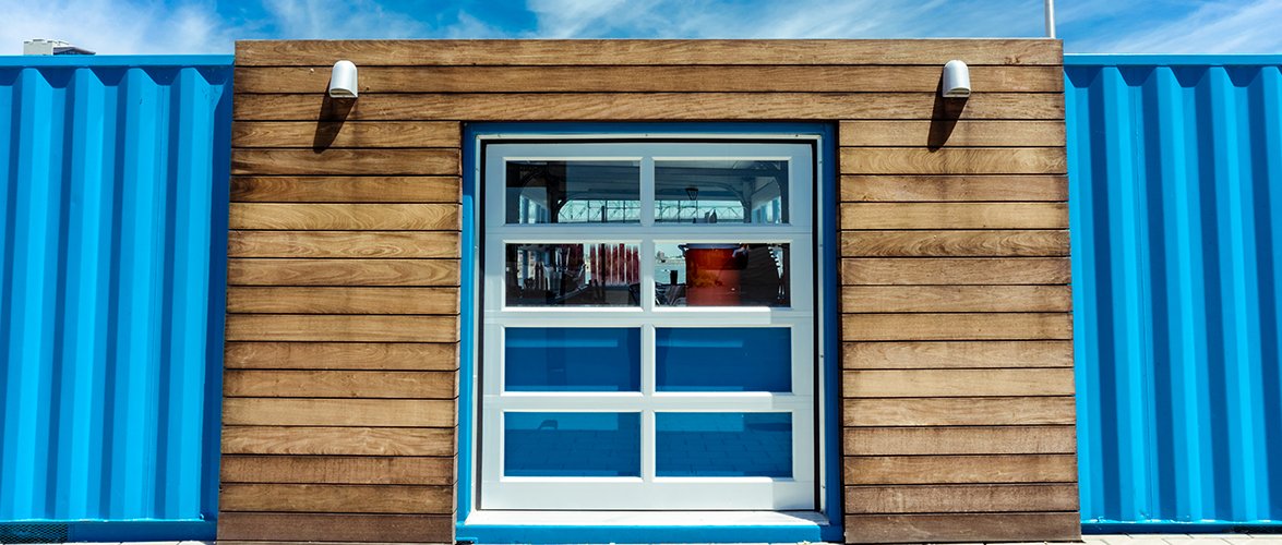 Eight-panel glass window on a blue tin and brown wood building.