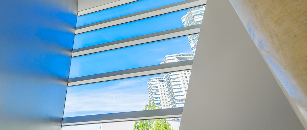 View of white apartment buildings from inside sleek window.