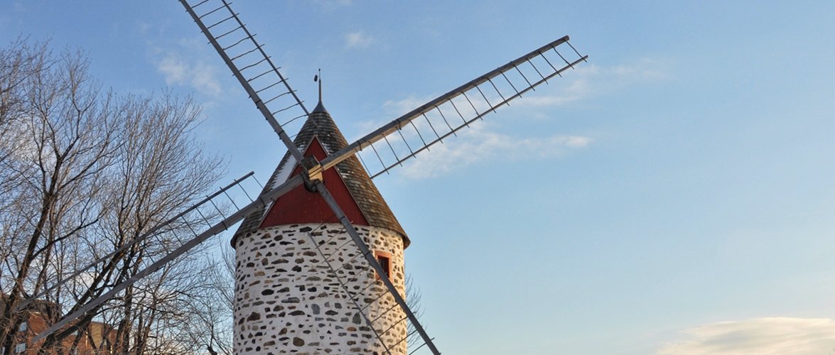 Old four-bladed stone windmill building with windows.